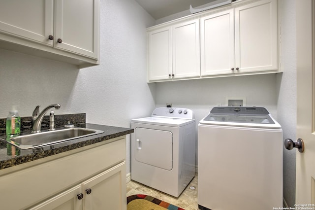 laundry room with a sink, cabinet space, a textured wall, and washing machine and dryer
