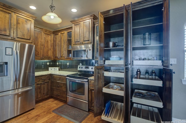 kitchen featuring light stone counters, tasteful backsplash, stainless steel appliances, and wood finished floors