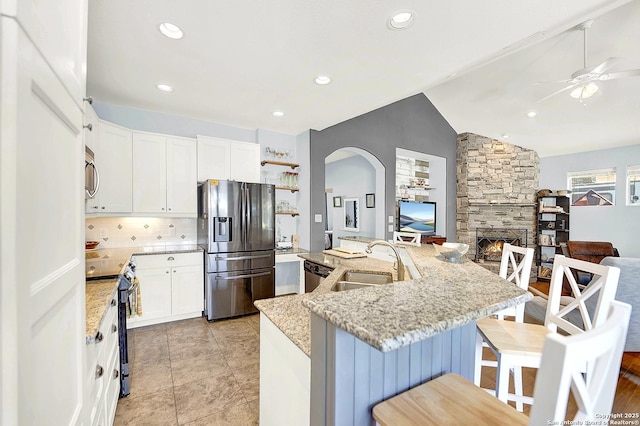 kitchen featuring ceiling fan, a sink, a kitchen breakfast bar, arched walkways, and stainless steel appliances