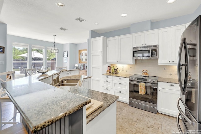 kitchen with decorative backsplash, visible vents, appliances with stainless steel finishes, a spacious island, and a sink