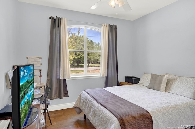 bedroom featuring baseboards, multiple windows, a ceiling fan, and wood finished floors