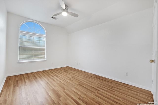 empty room featuring ceiling fan, light wood-style floors, baseboards, lofted ceiling, and visible vents