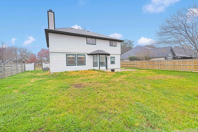 rear view of house with a fenced backyard, a chimney, and a yard