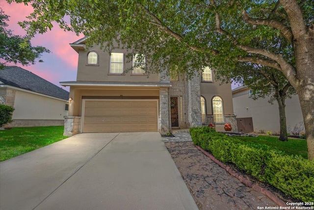 view of front of home with a garage, stucco siding, concrete driveway, and stone siding