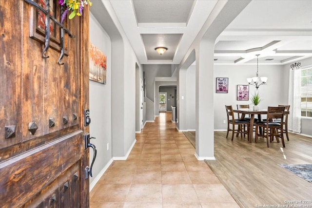 foyer with arched walkways, baseboards, a chandelier, and coffered ceiling