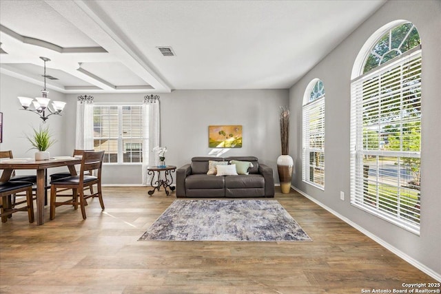 living area featuring visible vents, baseboards, wood finished floors, and a notable chandelier