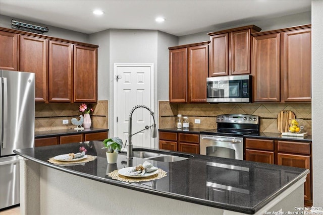 kitchen with recessed lighting, dark stone counters, a sink, appliances with stainless steel finishes, and backsplash