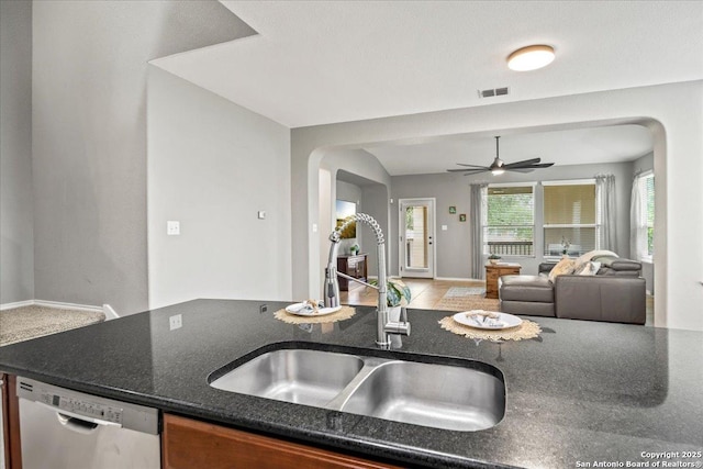 kitchen with a sink, dishwasher, arched walkways, open floor plan, and visible vents
