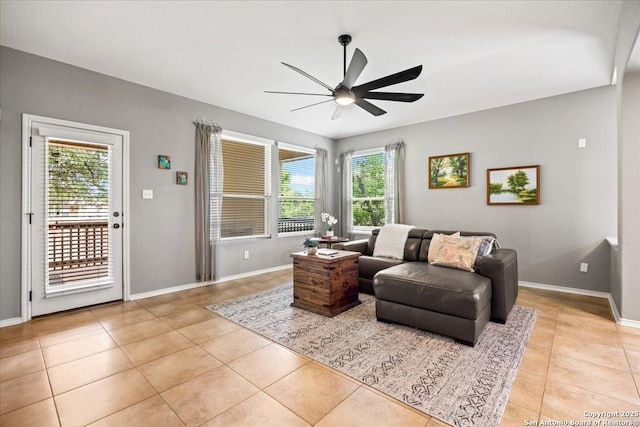 living room with light tile patterned flooring, ceiling fan, and baseboards