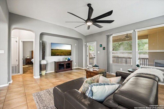 living room featuring a ceiling fan, visible vents, arched walkways, vaulted ceiling, and light tile patterned floors