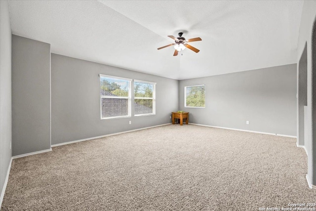 carpeted spare room with ceiling fan and baseboards