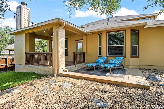 rear view of property featuring fence, a shingled roof, ceiling fan, a chimney, and a patio