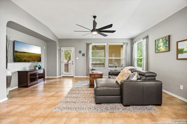 living area with baseboards, a ceiling fan, light tile patterned flooring, and a wealth of natural light