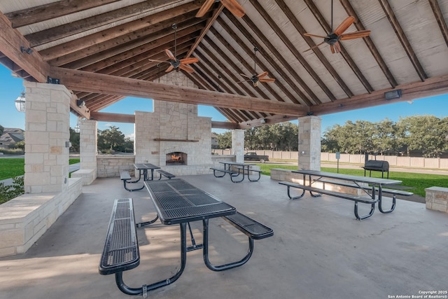 view of patio / terrace featuring an outdoor stone fireplace, ceiling fan, fence, and a gazebo