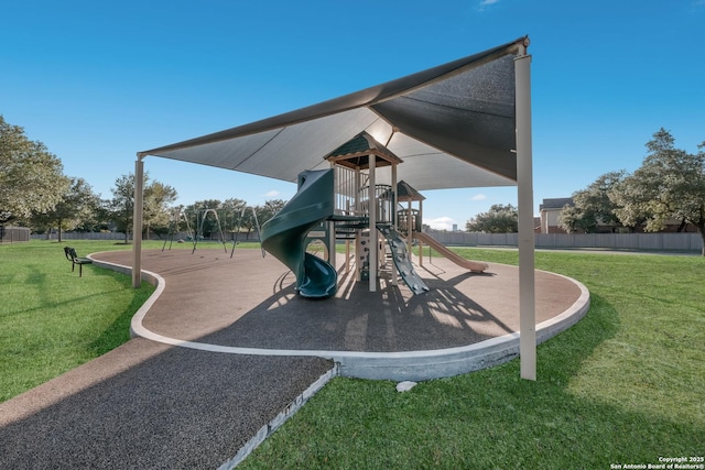 community jungle gym featuring a lawn and fence