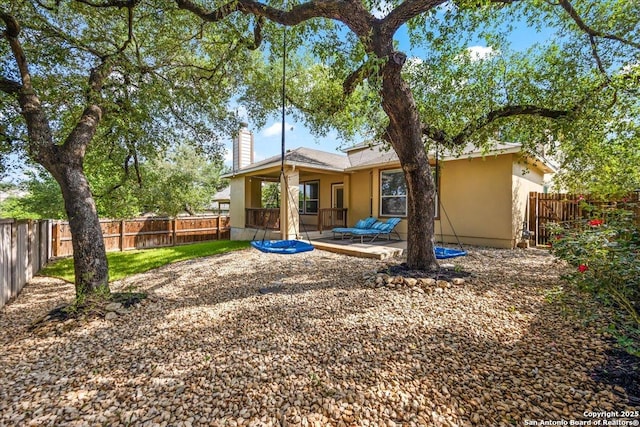 rear view of house with a chimney, a fenced backyard, a patio area, and stucco siding