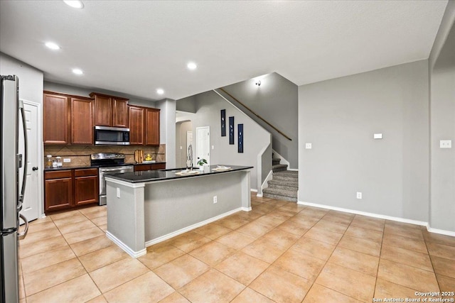 kitchen featuring light tile patterned flooring, dark countertops, tasteful backsplash, arched walkways, and appliances with stainless steel finishes