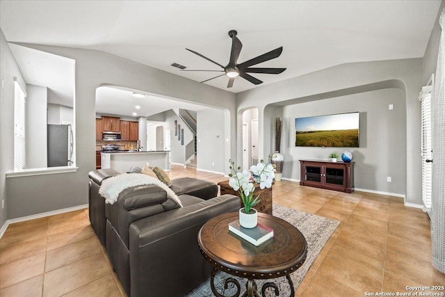 living room featuring light tile patterned floors, arched walkways, ceiling fan, and vaulted ceiling