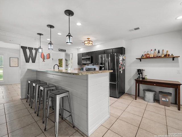 23 Sunrise, Pleasanton, TX 78064 - kitchen featuring a breakfast bar area, stainless steel appliances, a peninsula, and light tile patterned flooring