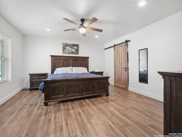 23 Sunrise, Pleasanton, TX 78064 - bedroom with baseboards, a barn door, and wood finished floors