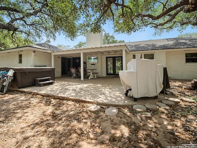 23 Sunrise, Pleasanton, TX 78064 - back of property featuring a hot tub, brick siding, french doors, and a patio area