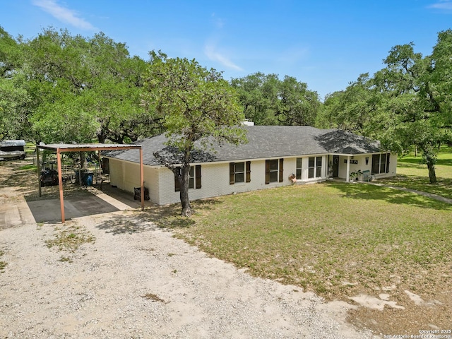 23 Sunrise, Pleasanton, TX 78064 - view of front of home featuring brick siding, dirt driveway, a front lawn, and a carport
