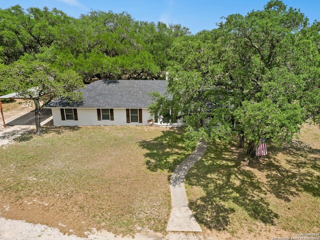 23 Sunrise, Pleasanton, TX 78064 - view of front facade with a carport, a shingled roof, and a front lawn