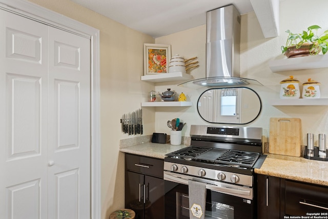kitchen with open shelves, light stone countertops, dark brown cabinetry, stainless steel range with gas cooktop, and range hood