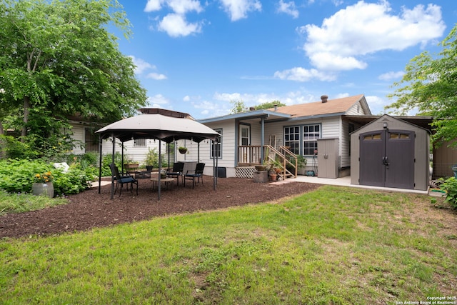 rear view of property with a storage shed, an outdoor structure, a gazebo, and a yard