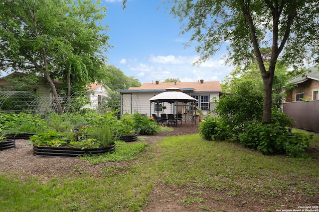 view of yard featuring fence, a gazebo, and a vegetable garden