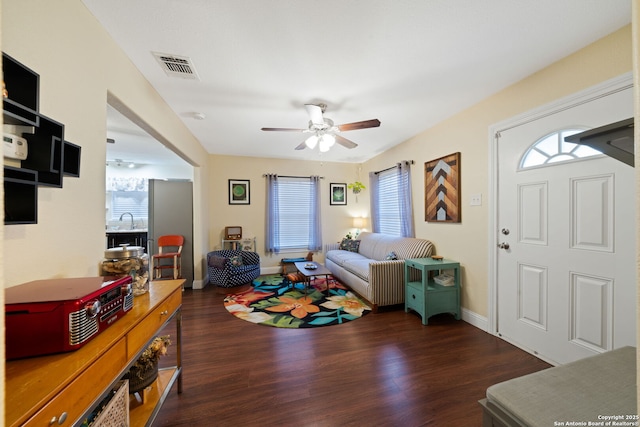 living area with baseboards, a ceiling fan, wood finished floors, and visible vents