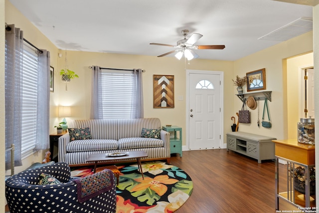 living room featuring a ceiling fan, visible vents, plenty of natural light, and wood finished floors