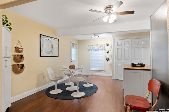 interior space with a ceiling fan, baseboards, and wood finished floors