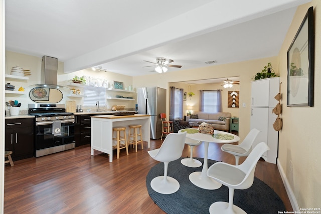 dining space featuring a ceiling fan, dark wood finished floors, a healthy amount of sunlight, and beamed ceiling