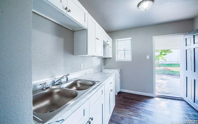 204 Division, San Antonio, TX 78214 - kitchen with dark wood-type flooring, light countertops, a textured ceiling, white cabinets, and a sink