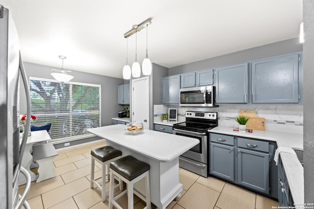 5211 Wood Gln, San Antonio, TX 78244 - kitchen with appliances with stainless steel finishes, a breakfast bar, light countertops, decorative light fixtures, and a kitchen island