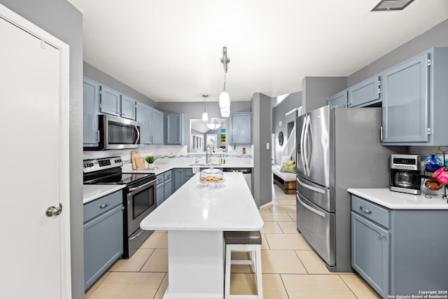 5211 Wood Gln, San Antonio, TX 78244 - kitchen featuring pendant lighting, a kitchen island, light countertops, appliances with stainless steel finishes, and light tile patterned floors