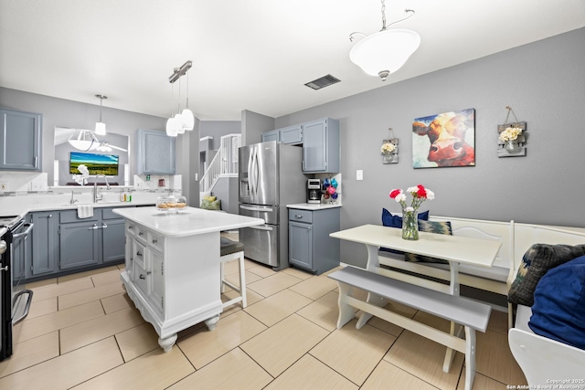 5211 Wood Gln, San Antonio, TX 78244 - kitchen featuring appliances with stainless steel finishes, a sink, light countertops, decorative light fixtures, and a kitchen island