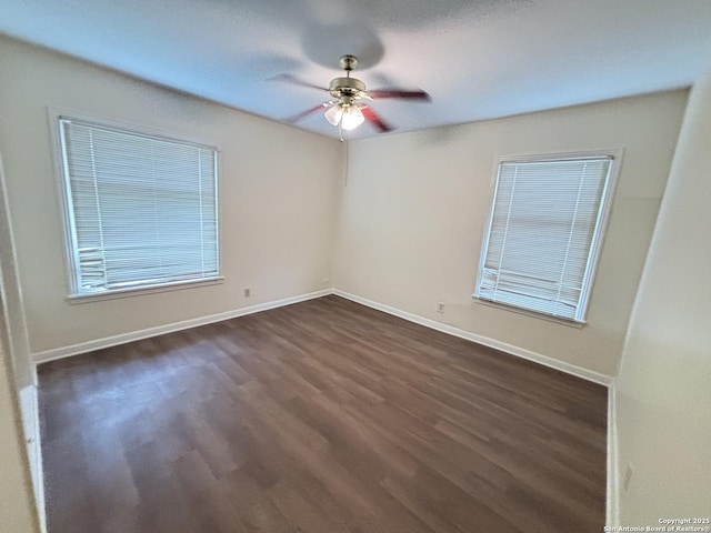 unfurnished room with baseboards, dark wood-style flooring, and ceiling fan
