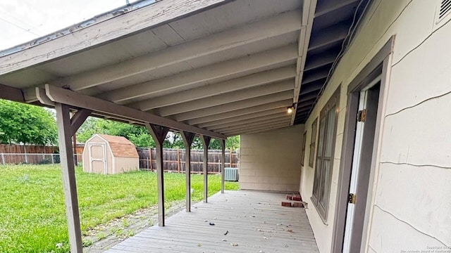 deck with a fenced backyard, a lawn, and a storage shed