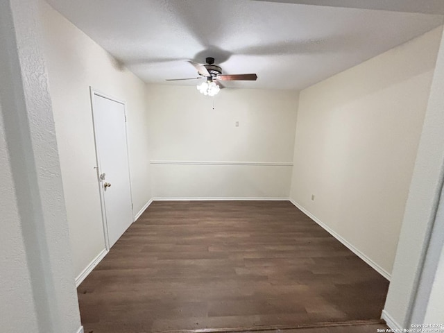 empty room with baseboards, a ceiling fan, and dark wood-style floors