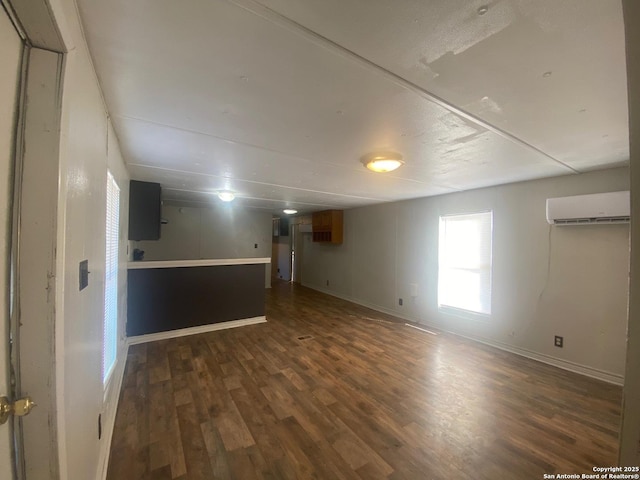 basement featuring baseboards, a wall mounted air conditioner, and dark wood-style floors