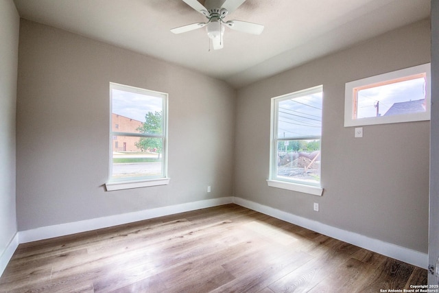 empty room featuring baseboards, plenty of natural light, a ceiling fan, and wood finished floors