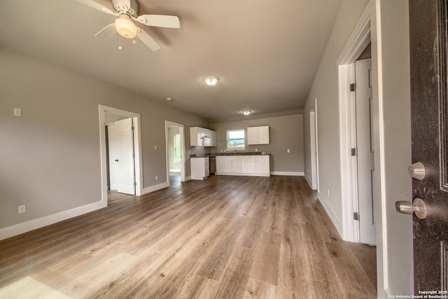 unfurnished living room with baseboards, a ceiling fan, and light wood-style flooring