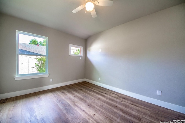 empty room featuring baseboards, ceiling fan, wood finished floors, and vaulted ceiling