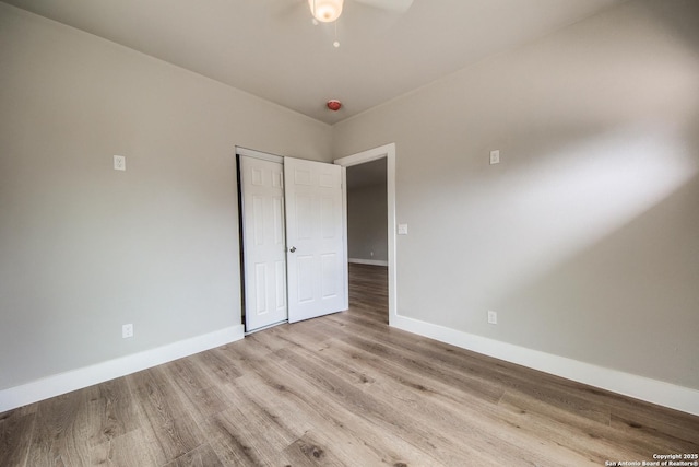unfurnished bedroom featuring baseboards, light wood finished floors, and a closet