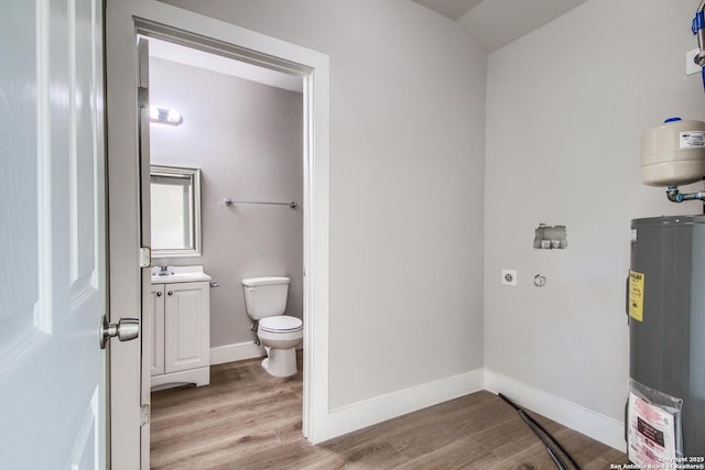 laundry room with light wood-type flooring, baseboards, water heater, and electric dryer hookup