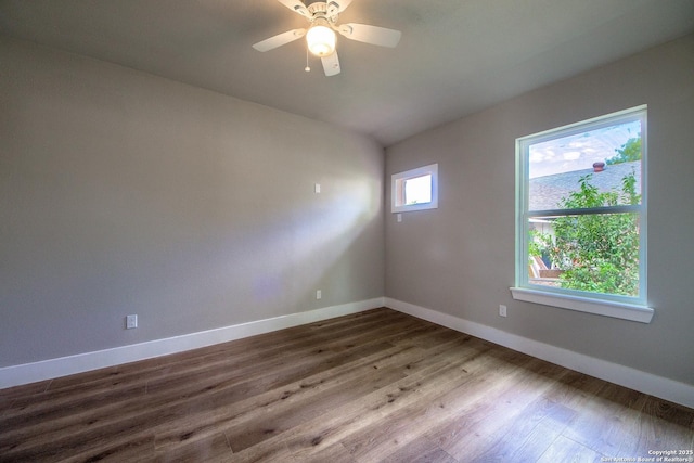 spare room featuring vaulted ceiling, baseboards, a ceiling fan, and wood finished floors