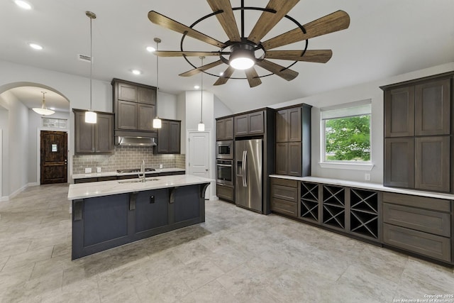 kitchen with appliances with stainless steel finishes, arched walkways, a ceiling fan, tasteful backsplash, and under cabinet range hood