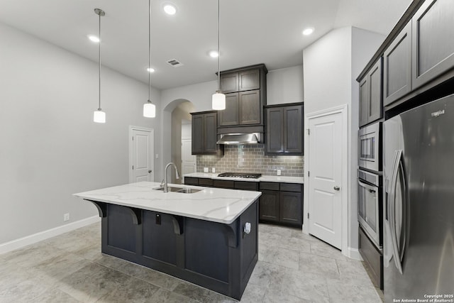 kitchen featuring visible vents, appliances with stainless steel finishes, tasteful backsplash, arched walkways, and a sink